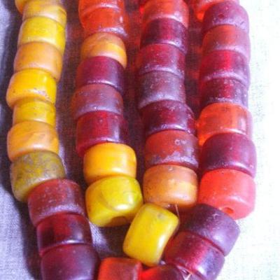 Collection of yellow/red glass beads, made in Bohemia in the 1960-70's and exported to Ethiopia for use by different tribes in the South. The yellow beads are made to imitate amber. Diam. 30 x 17 cm.