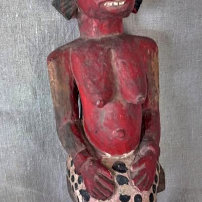 Brightly painted statue of a seated female, hands on the knees. The toes on the right-foot have been ritually removed. Well-used figure. Height: 47cm. Senoufo, Ivory-Coast.